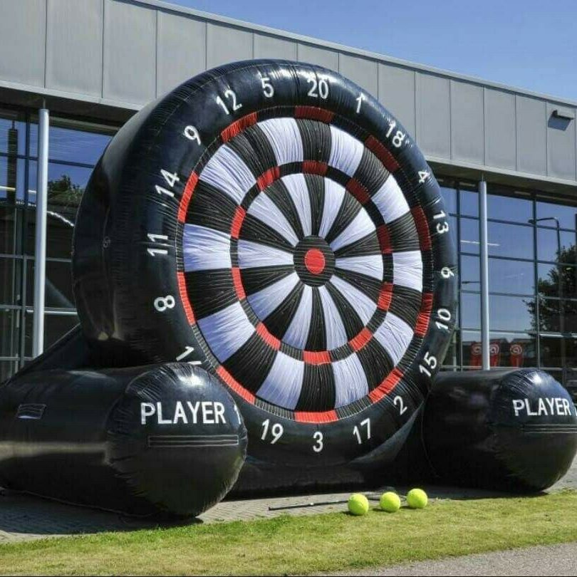 Our Big Impact Giant Inflatable Dartboard game set up to look visually impressive, with a man in action, kicking a football to get a score at a Corporate Fun Day event.