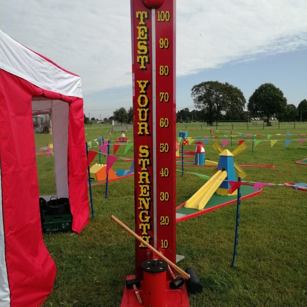 Traditional High Striker set up ready for play with a Side Stall, Crazy Golf and lots of bright bunting for a Village Fair or Fete.