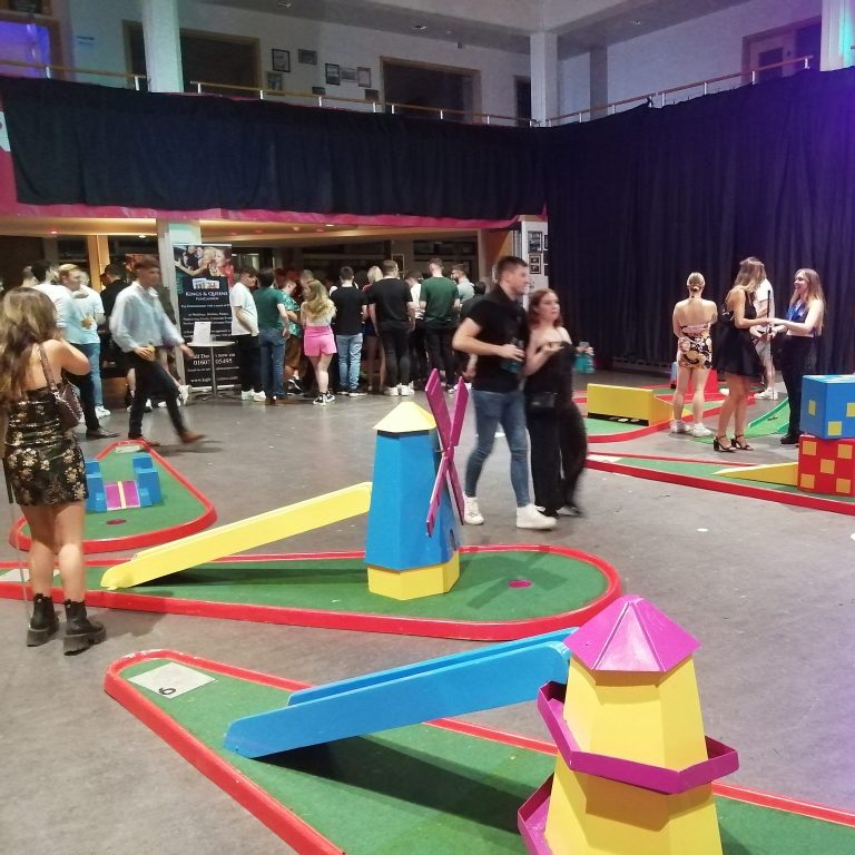 Our popular Crazy Golf with a large group of students watching and playing in a University hall for a Freshers Fayre event.