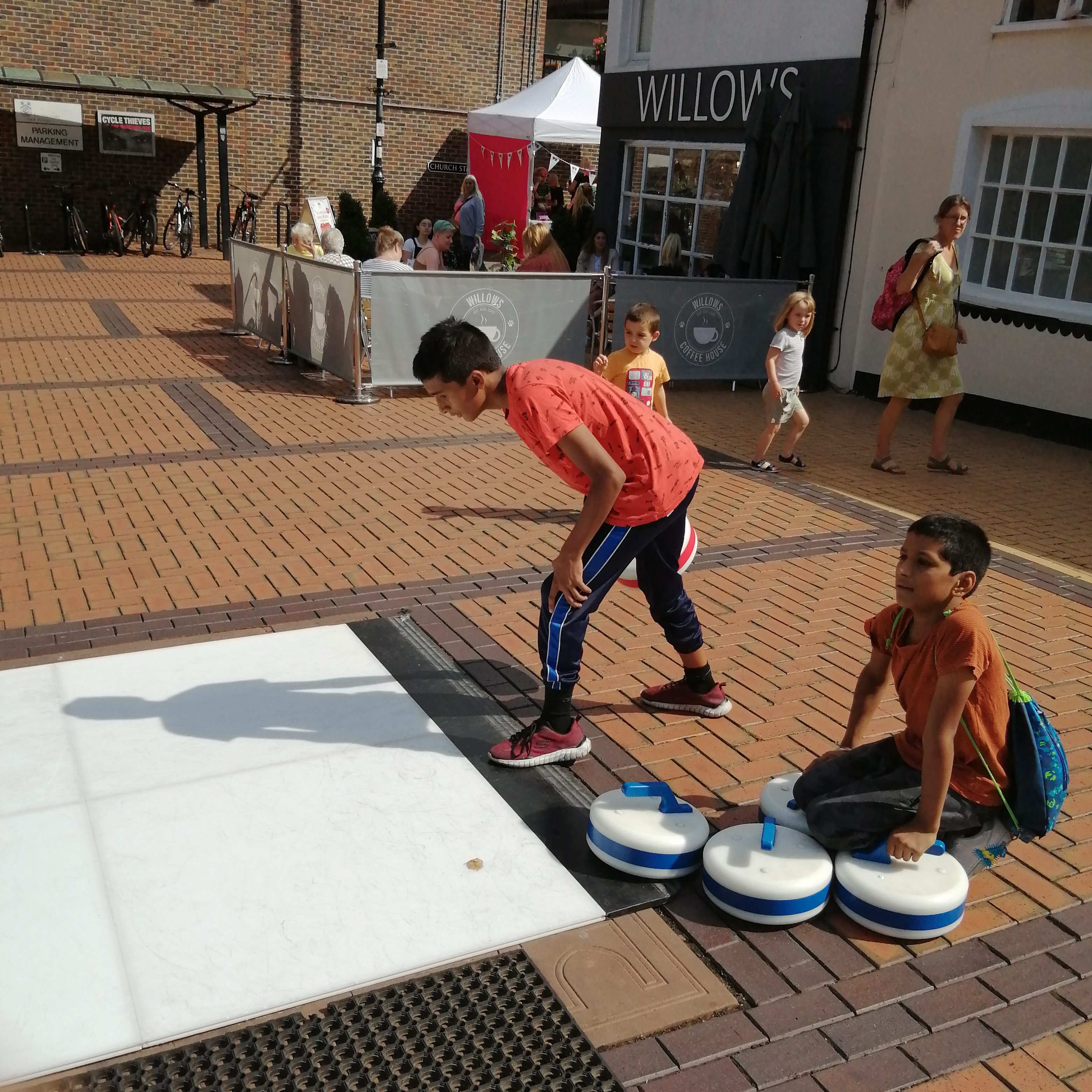 People playing Curling on a sunny day, at a Street event.