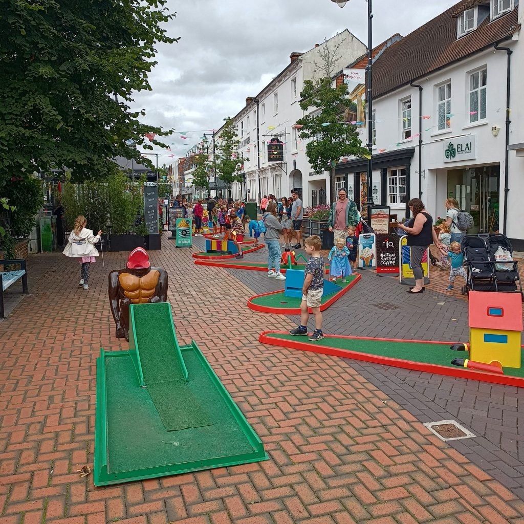A town centre with crowds of people enjoying our hired in Crazy Golf, with our famous Gorilla Putt Challenge in clear view.