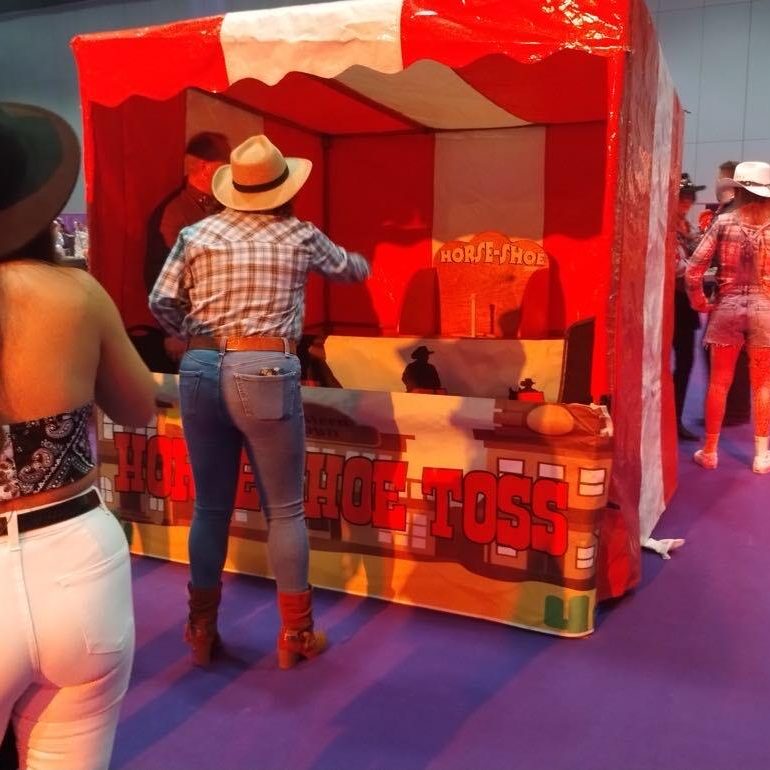 Adults at a Western themed office party throwing horseshoes at the target which is inside one of our hired Side Stalls.