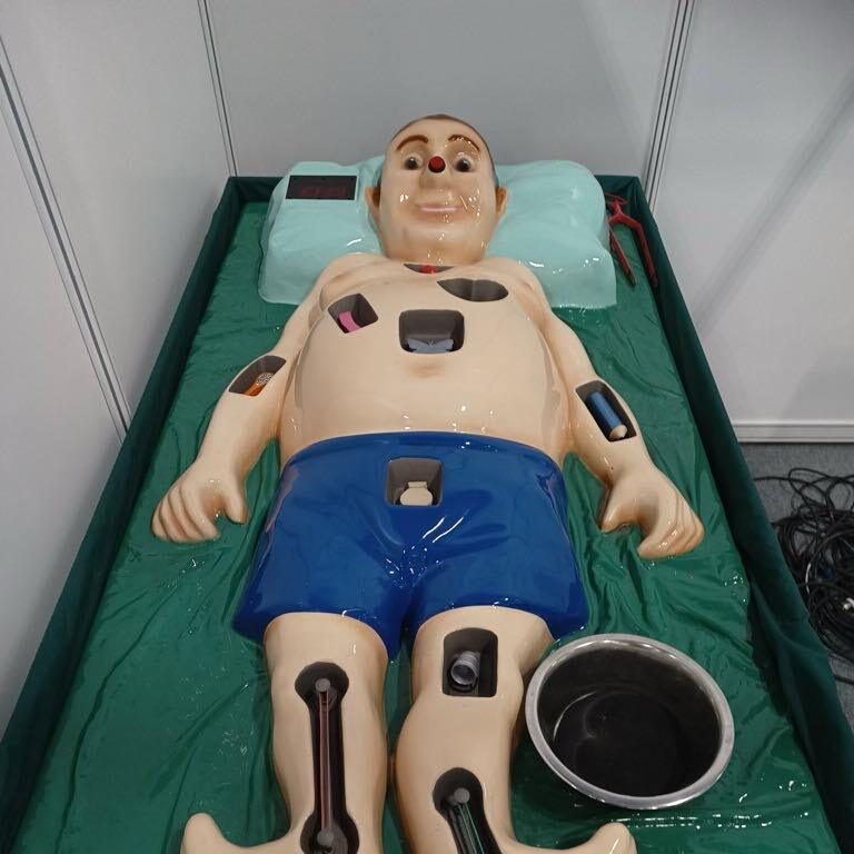 Plastic 3D man on a bed with holes for various different plastic body parts to be placed in order for people to try and retrieve them without setting off the loud buzzer.