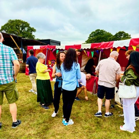 Summer event with our hired in red and white striped Fete Game Side Stalls in a row with people watching and playing