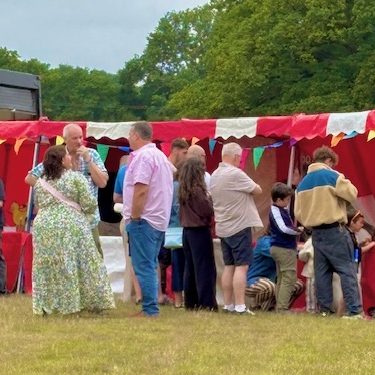 Summer event with our hired in red and white striped Fete Game Side Stalls in a row with people watching and playing.