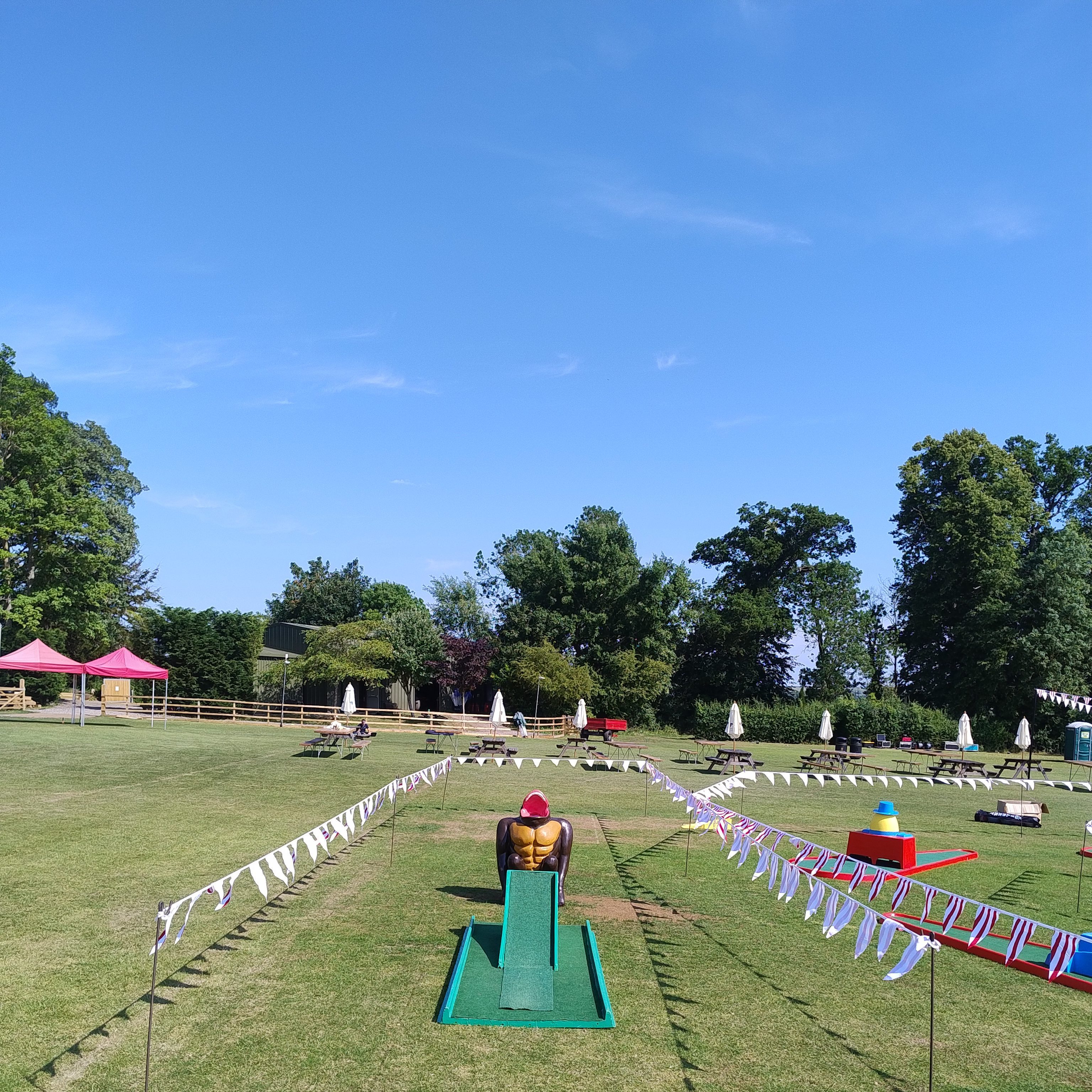Our infamous Gorilla Golf Putt Challenge with Crazy Golf in the background, decorated with brightly coloured bunting and happy, focused children playing.