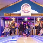 A group of people at a Kings Cross Station event having a go at our Curling Lane.