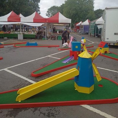Close up of Crazy Golf and brightly painted obstacles set out in a car park for a Town Market event.