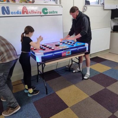 A man and child playing against each other with one of our hired Electronic Competitive games known as Chase the Lights.