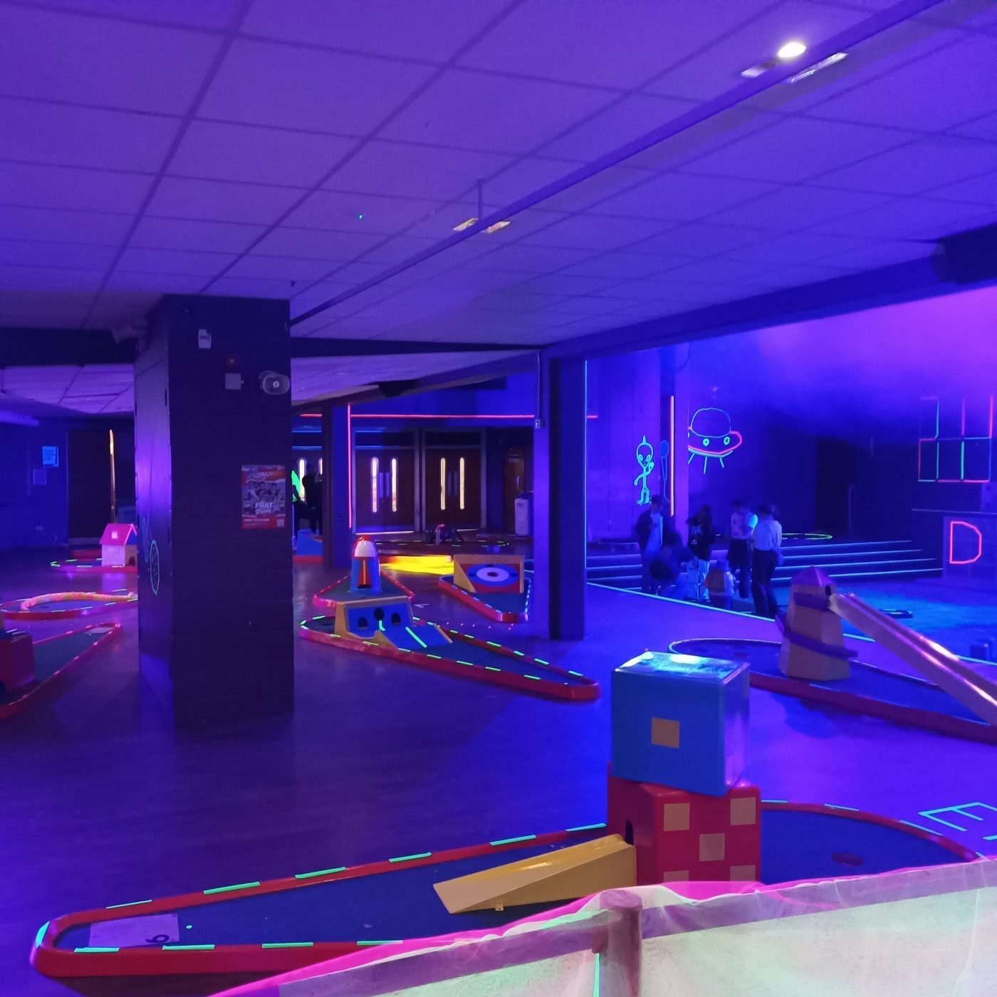 Our Crazy Golf decorated with UV tape and neon lights set up ready for an indoor University event.