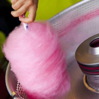 An adult in action spinning sugar to make Candyfloss at a Village Fete.