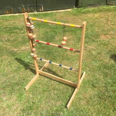 Our wooden Ladder Golf set out on grass, with the red and blue bolas positioned ready for play.