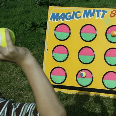 A child stood in front of our brightly painted Magic Mitt game, with a ball poised ready for a throw.